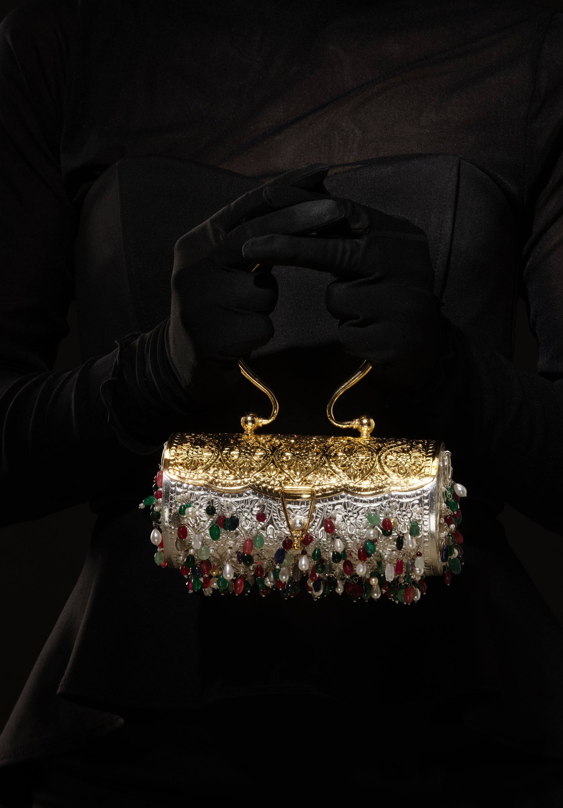 Elegant 925 silver handbag with semi precious gemstones held by a gloved hand against a dark background